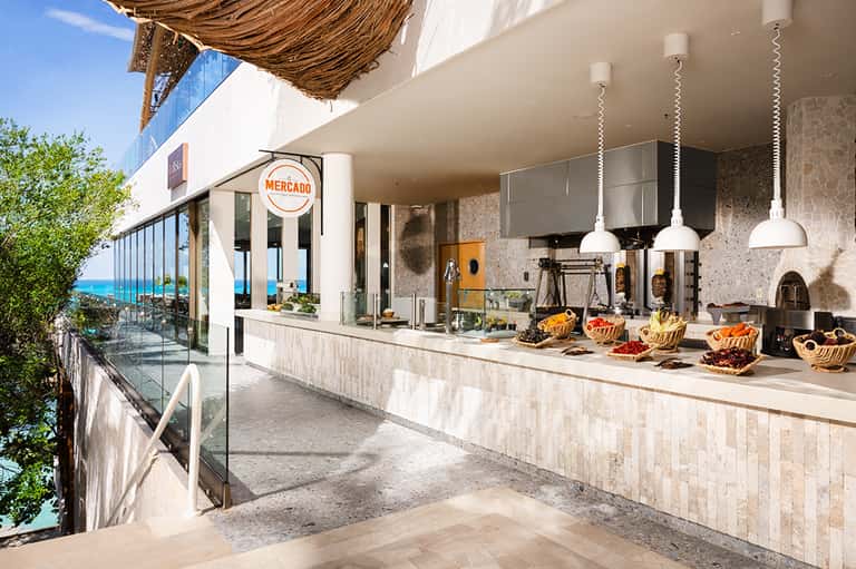 Beachfront restaurant counter with woven shade, stainless steel kitchen, and ocean view
