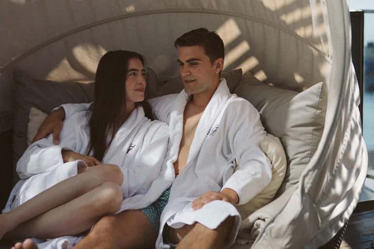Couple relaxing in white bed canopy with ocean view in background