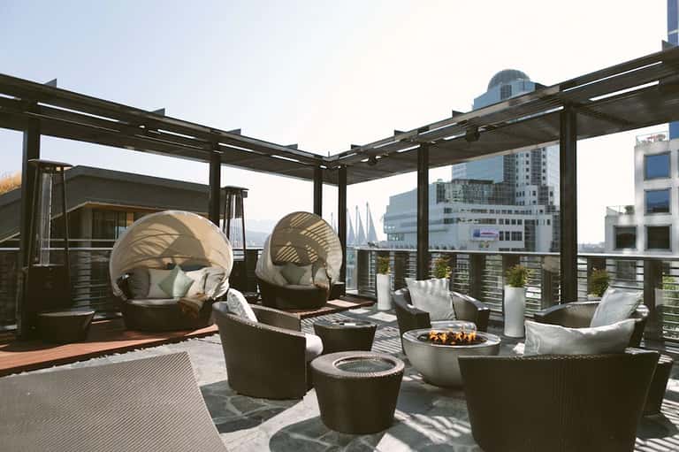 Luxury rooftop lounge with egg chairs, fire pits, and urban cityscape views