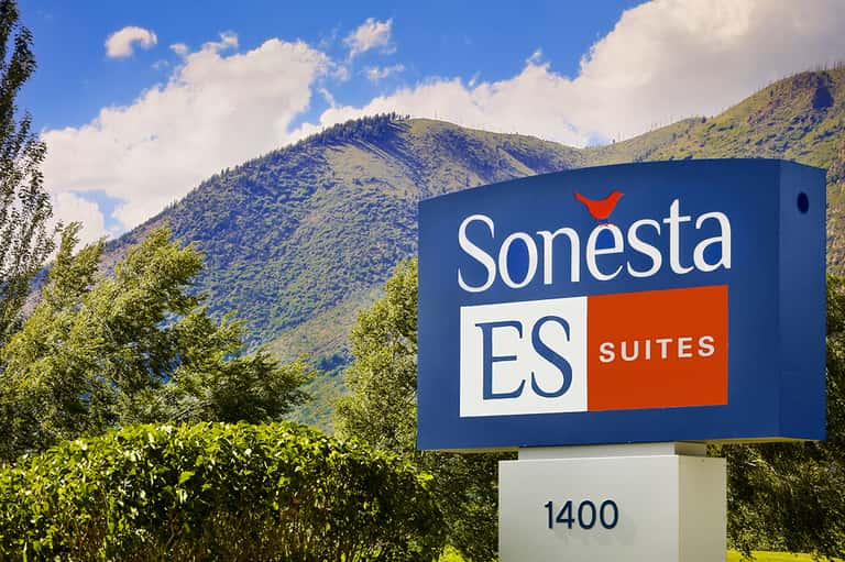Sonesta ES Suites sign with mountains in background, blue and orange branding