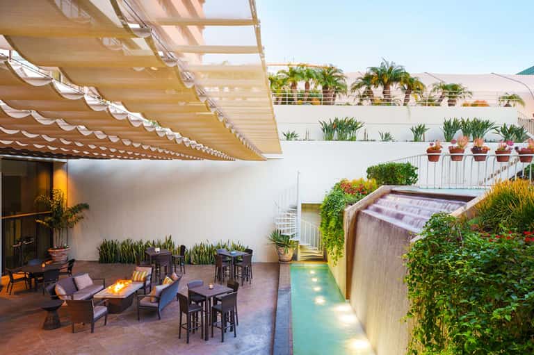 Rooftop lounge with striped awning, fire pit, small pool, and tiered garden seating