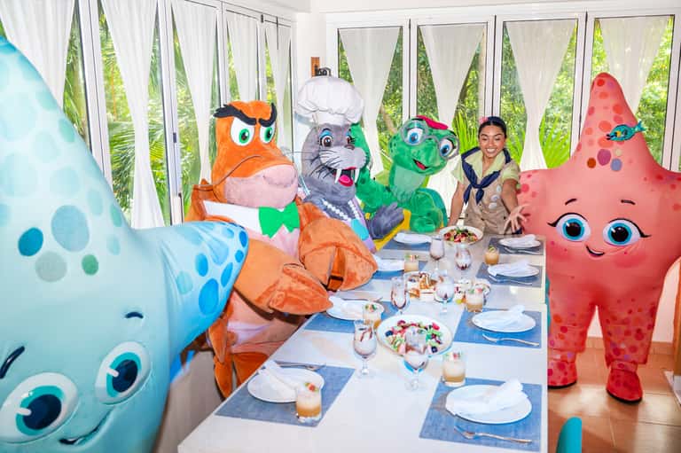 Themed character dining experience with costumed mascots seated at elegant table setting
