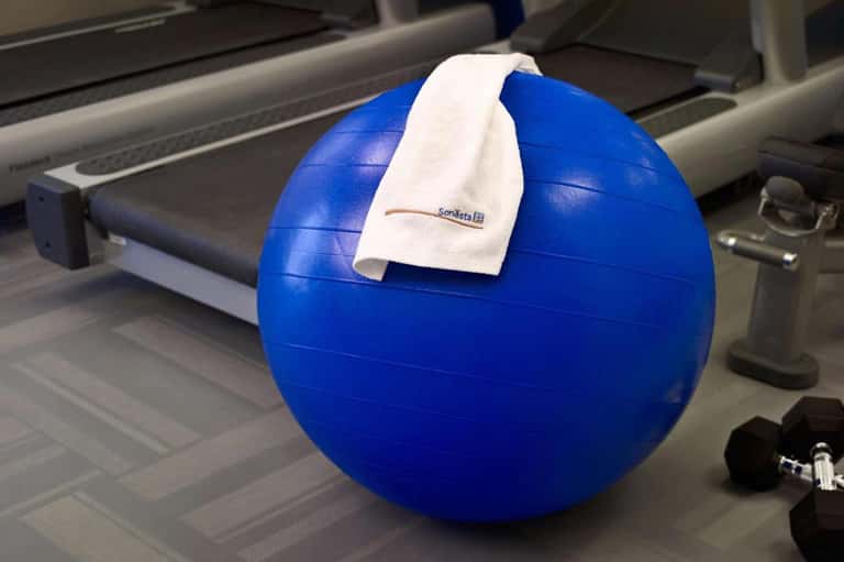 Blue exercise ball with white towel in fitness center near treadmill