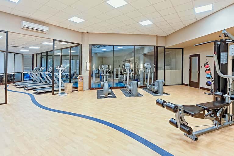 Fitness center with cardio equipment, large windows, and blue floor stripe accents