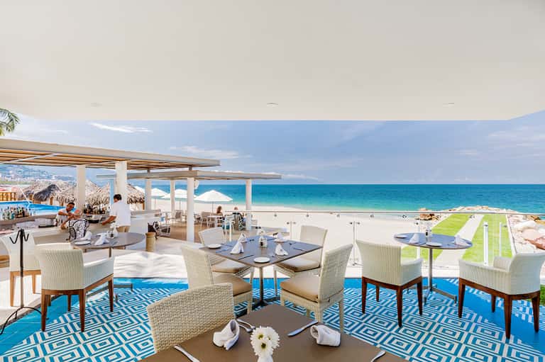 Beachfront restaurant with ocean views, white pergolas, and modern furnishings