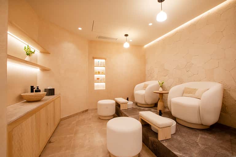 Luxury spa lounge with curved cream chairs, wooden accents, and ambient lighting