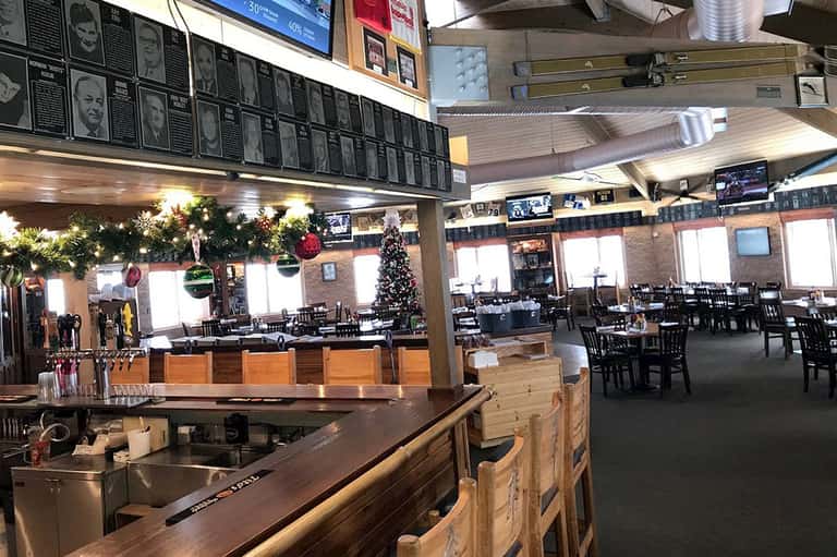 Sports bar restaurant interior with menu board, seating, and holiday decorations