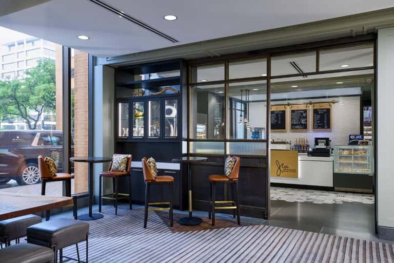 Hotel cafe interior with modern seating, floor-to-ceiling windows, and service counter