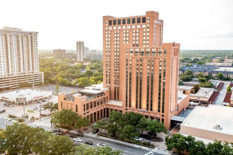 Tall red brick hotel tower in urban setting with surrounding buildings