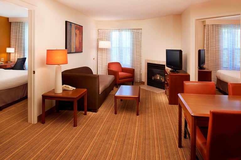 Suite living room with fireplace, orange accents, sofa, and bedroom access