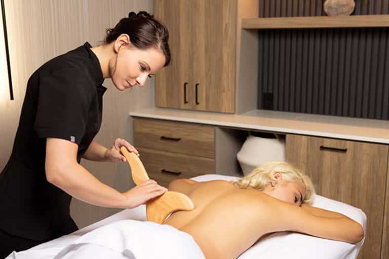 Spa massage treatment room with therapist performing back massage on relaxed client