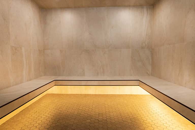Empty marble bathroom with hexagonal tile floor and ambient golden lighting accent strip