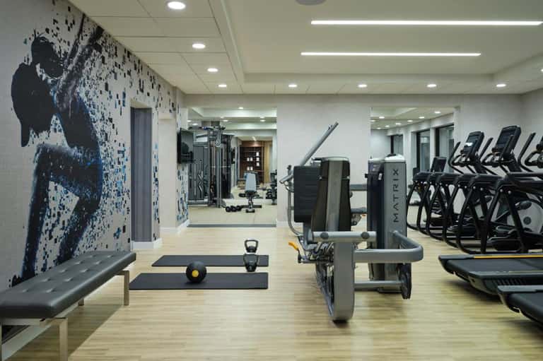 Fitness center with treadmills, weight equipment, artistic wall mural, and modern design