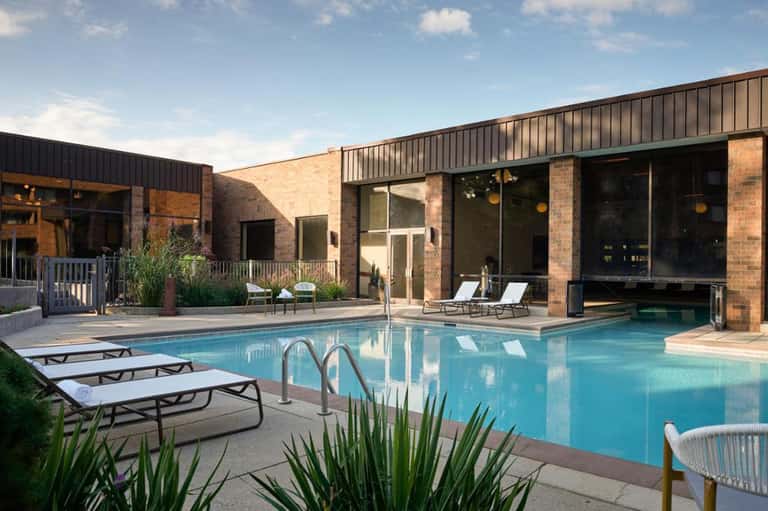 Resort swimming pool with lounge chairs, modern brick building, and clear blue water