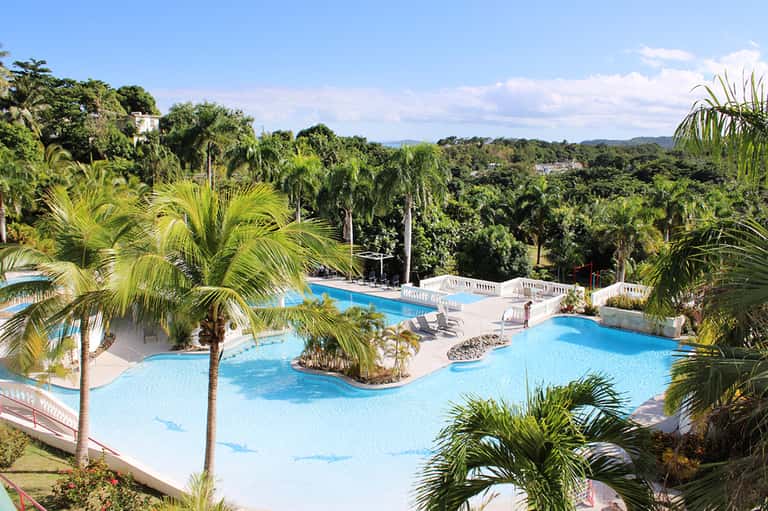 Multi-level resort pool complex with palm trees and scenic landscape view