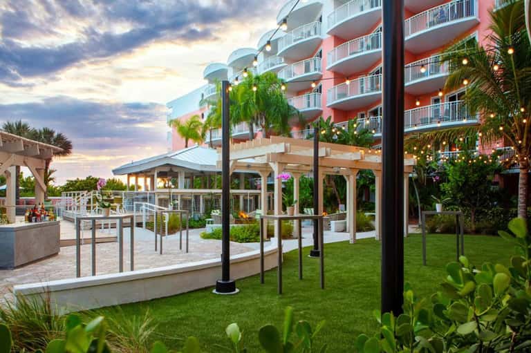 Resort courtyard at dusk with wooden pergolas, manicured lawn, residential towers, and lighting