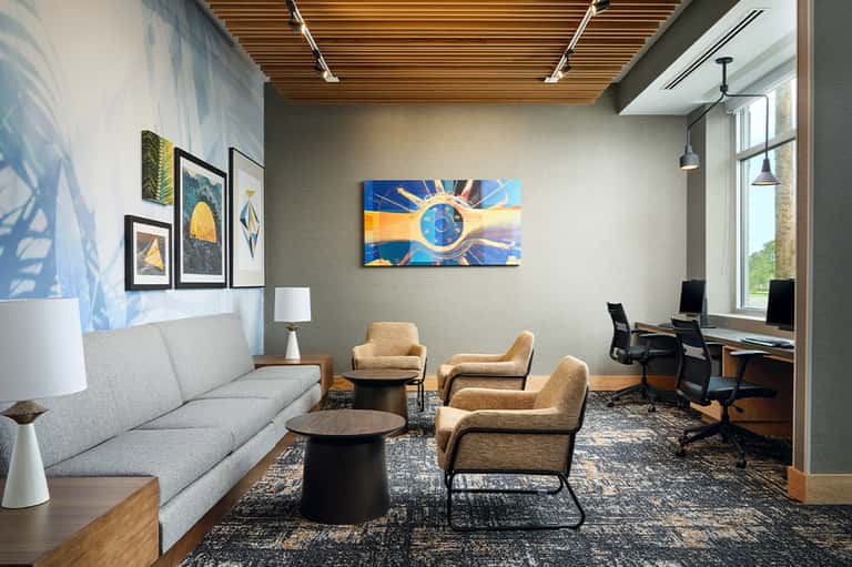 Contemporary business lounge with modern artwork, wooden ceiling, and work stations