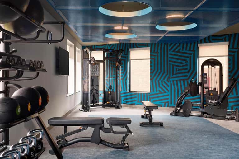 Modern hotel fitness center with blue geometric wall patterns, exercise equipment, and contemporary design