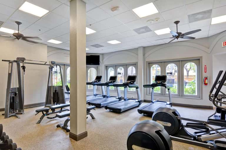 Modern fitness center with treadmills, exercise equipment, and arched windows