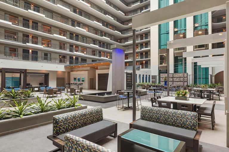 Modern hotel atrium courtyard with multi-level balconies, lounge seating, and contemporary architectural design