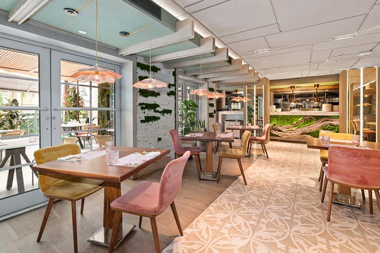 Contemporary restaurant interior with mid-century furniture, living walls, and pendant lights