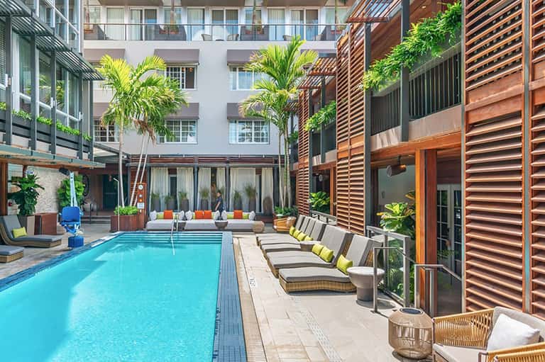 Urban resort courtyard with rectangular lap pool, wooden screens, and lounge seating