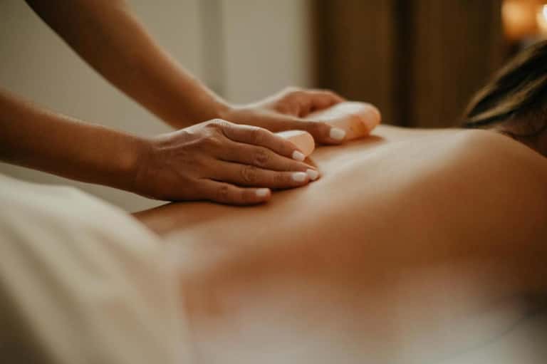 Massage therapist's hands performing treatment on client's back in spa setting