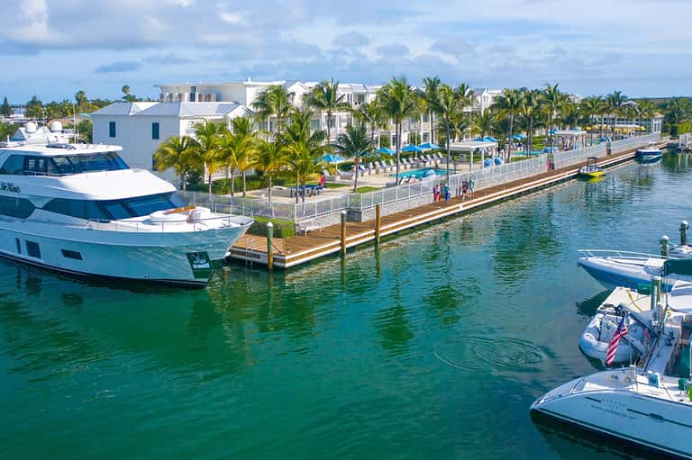 Waterfront marina with luxury yacht, boats, and white waterfront resort buildings