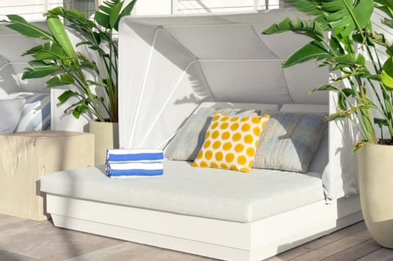 Modern bedroom with white bed, yellow polka dot pillow, potted plants, and sailboat art