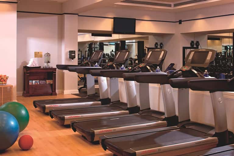 Modern hotel fitness center with multiple treadmills, mirrors, and exercise equipment