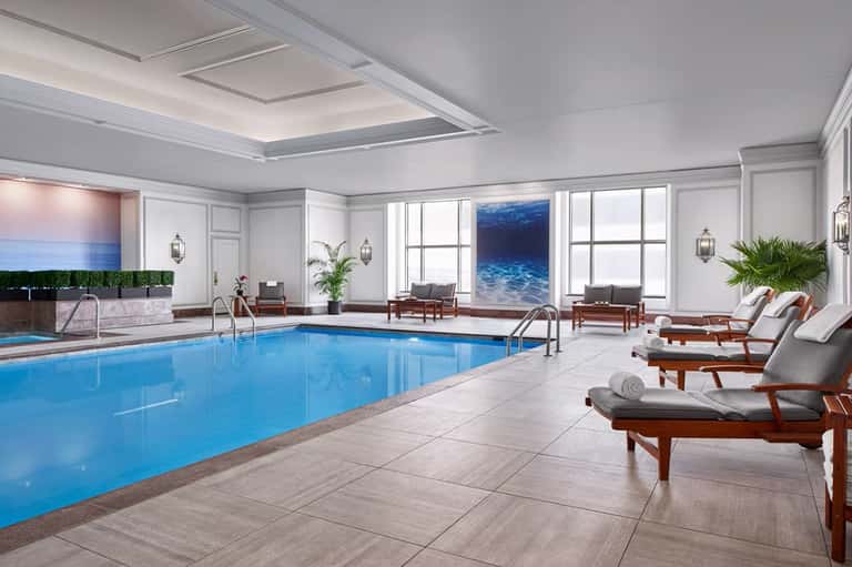 Indoor heated pool with lounge chairs and ocean view windows
