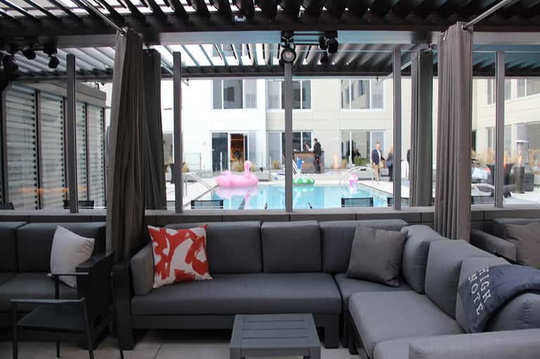 Contemporary covered patio with gray sectional sofa overlooking resort pool