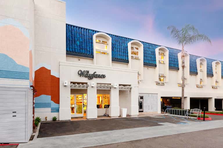 Retro-style beachside building with cream facade, blue roof detail, and palm tree