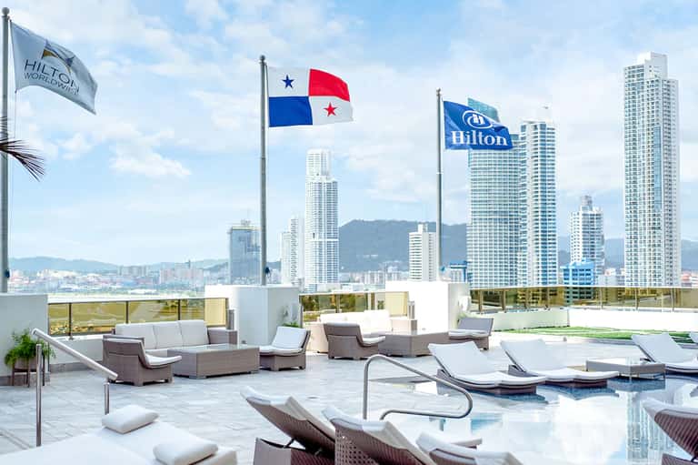 Rooftop terrace with pool, loungers, and city skyline views