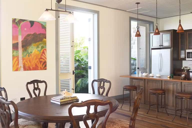 Modern kitchen and dining room with wood furnishings, colorful art, and tropical view