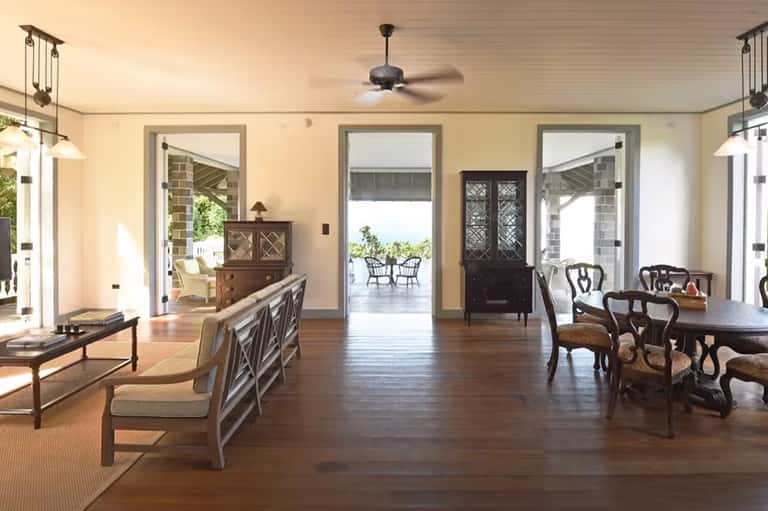 Elegant lakeside room with wood flooring, furniture, and open doors to waterfront deck