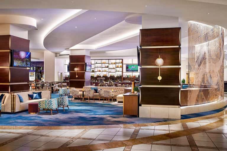 Spacious modern hotel lobby with curved architectural elements, lounge seating, bar, and contemporary design features