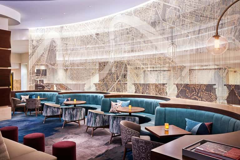 Modern hotel lounge with teal curved seating, decorative wall mural, and contemporary furnishings