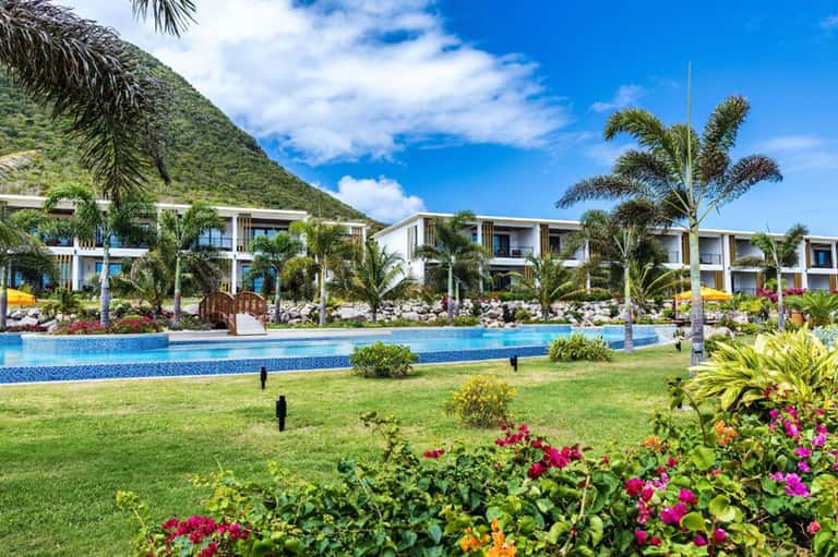 Modern resort grounds with white buildings, lagoon-style pool, and tropical landscaping