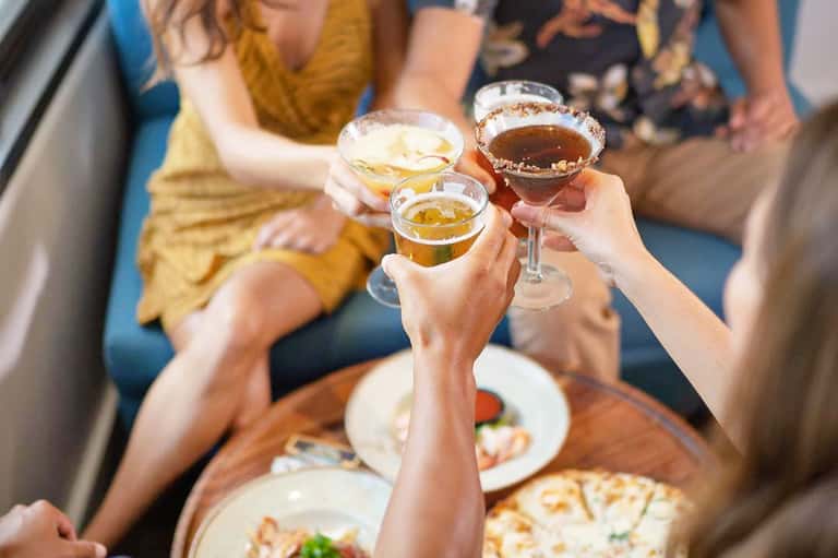 Group of people toasting with cocktails at a social gathering indoors