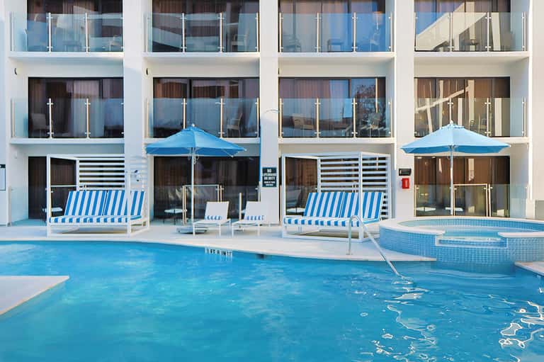 Modern beachfront pool with blue striped loungers and glass balconies above