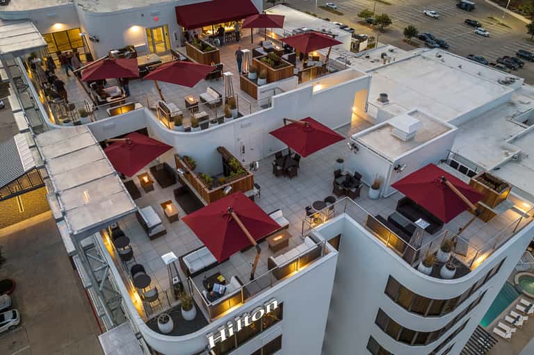 Aerial rooftop view of hotel terraces with burgundy umbrellas and lounge seating areas