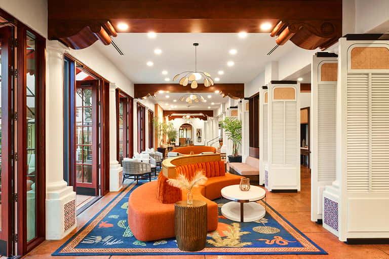 Stylish resort hallway with orange curved seating, wooden accents, and elegant lighting fixtures