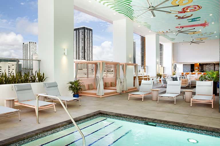 Rooftop pool deck with loungers, cabana, and city skyline views