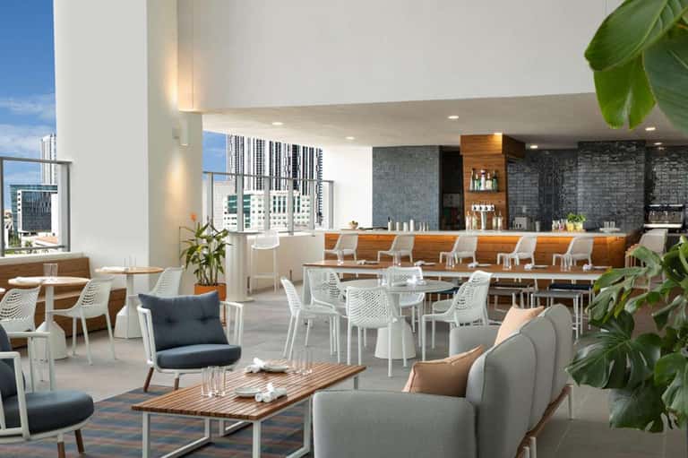 Upscale rooftop bar and lounge with city skyline views, modern seating, and wood accents