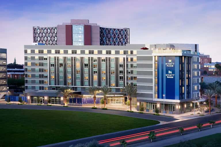 Modern Hyatt Place hotel exterior at dusk with illuminated façade and manicured lawn