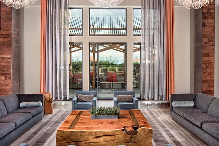 Luxury lounge with floor-to-ceiling windows, modern sofas, and terrace access with rustic accents
