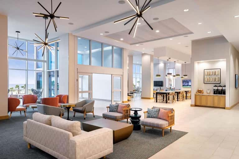 Modern hotel lobby with contemporary lighting fixtures, seating areas, and floor-to-ceiling windows