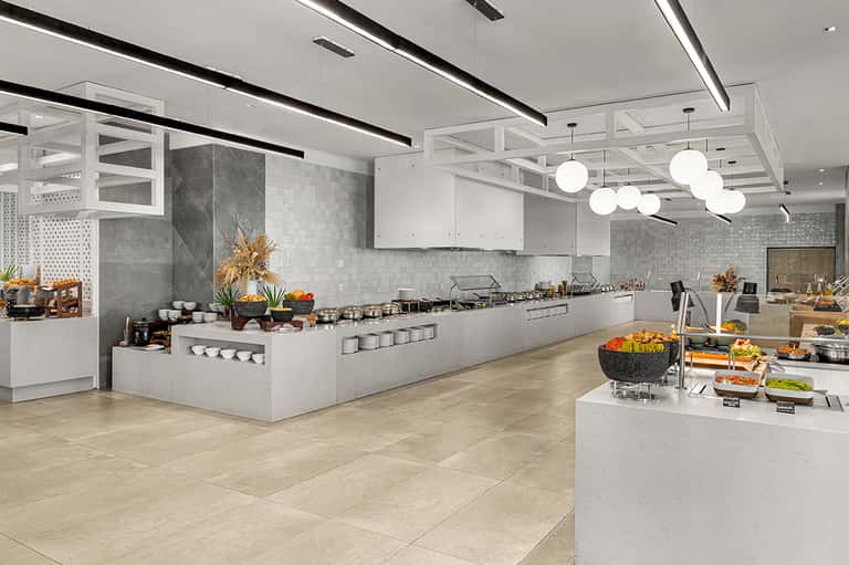 Modern hotel kitchen with white cabinetry, gray tile backsplash, stainless steel appliances