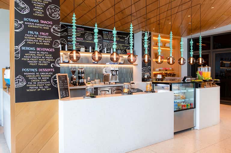 Bright cafe counter with turquoise pendant lights, wooden ceiling, and chalkboard menu board